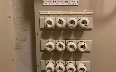 Säkringsskåp med keramikproppar, alla märkta MAX 20 A. En diskussion om prisskillnad mellan 16 A och 20 A säkringar kan uppstå.