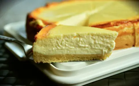 Una rebanada cremosa de tarta de queso Philadelphia, con su base dorada y relleno suave, lista para ser disfrutada.