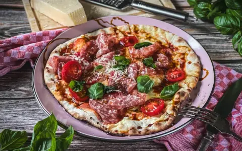 Leckere italienische Pizza mit Salami, Tomaten und Basilikum. Ein wahrer Genuss für alle, die italienische Rezepte lieben.
