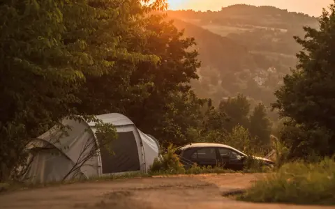 Namiot i samochód na tle malowniczego krajobrazu o zachodzie słońca. Idealne miejsce na **camping Kraków**.