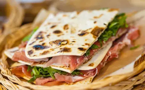 Piadina romagnola con prosciutto crudo e rucola, un'ottima opzione per chi cerca dove mangiare a Rimini.