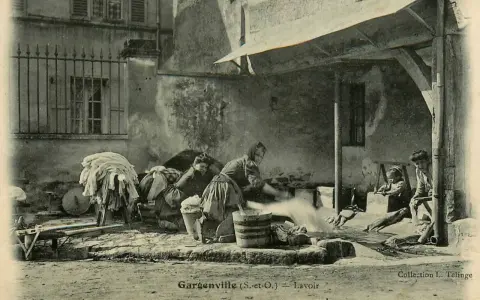 Des femmes s'affairent à laver le linge autrefois, dans une cour. Des enfants observent ce travail pénible.