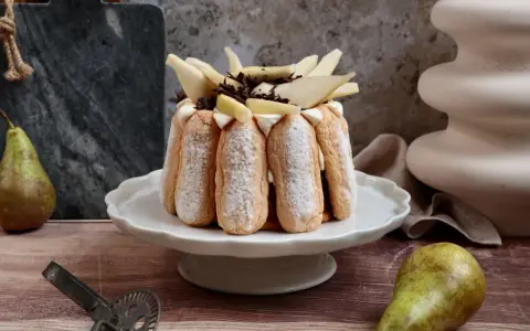Charlotte poire chocolat, un dessert élégant avec des biscuits à la cuillère, garni de poires fraîches et de copeaux de chocolat.