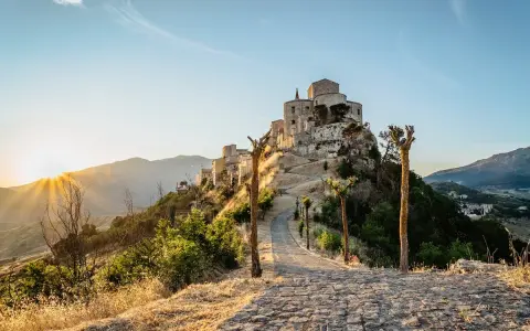Petralia Soprana: cosa vedere in questo borgo arroccato, con un sentiero in pietra che sale verso il castello al tramonto.
