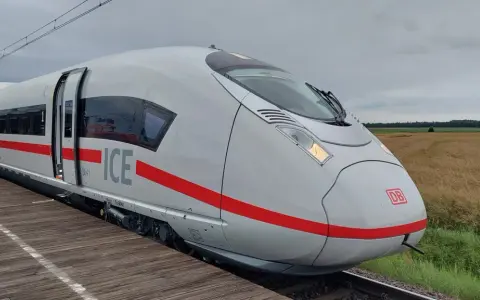 Nowoczesny, biały pociąg ICE 3neo z czerwonym pasem, stojący na peronie.