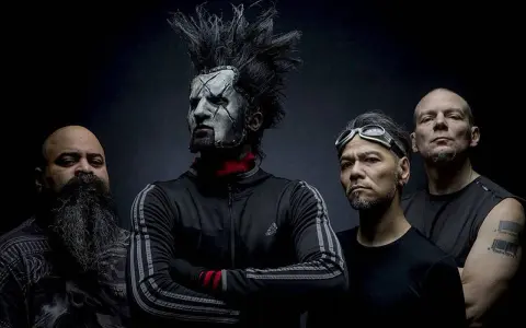 Quatre hommes, dont un avec un maquillage facial blanc et une crête, posent pour une photo. Le groupe Static X semble prêt à monter sur scène.
