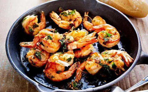 Saftige Garnelen in Knoblauchöl, ein Klassiker der italienischen scampi rezepte. Dazu Baguette.