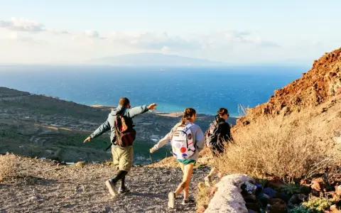 Vandrare njuter av utsikten över havet och landskapet på Santorini. En man pekar ut mot horisonten.