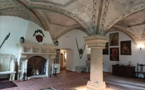 Wnętrze pałacu w Ciechanowicach z kamiennym kominkiem, malowanym sklepieniem i portretami na ścianach.