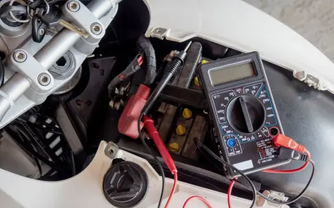 Multimetro collegato alla batteria di uno scooter per verificarne lo stato, un passo fondamentale per capire come caricare batteria scooter.