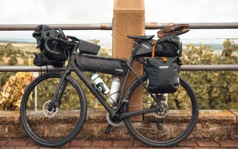 Bereit für die nächste gravel tour: Ein voll beladenes Gravelbike mit Ortlieb-Taschen, Trinkflaschen und sogar Schuhen auf dem Gepäckträger.