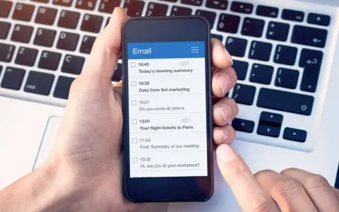 Dłoń trzyma smartfon z listą e-maili, w tym "Your flight tickets to Paris". Kiedyś, yours sincerely, wysłałbym takie wiadomości.