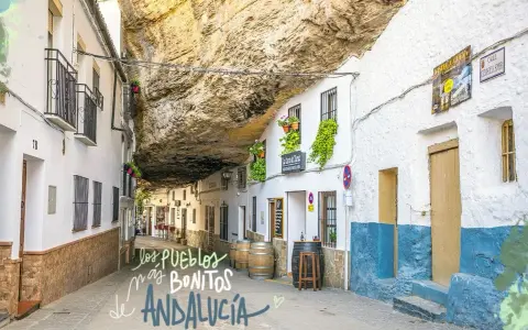 Calle bajo roca en Setenil de las Bodegas, uno de los pueblos mas bonitos de Andalucia. Casas blancas con balcones floridos y barriles de vino.