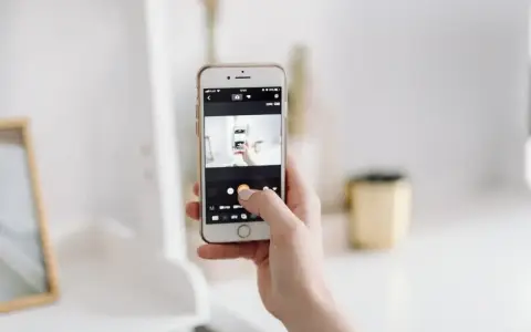 Dłoń trzyma smartfon, na ekranie którego widać aplikację do robienia zdjęć. To jakby snapbridge po polsku, ułatwiający dzielenie się wspomnieniami.