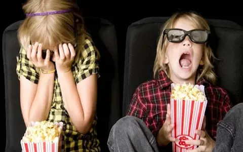 Dzieci w kinie, kiedy pierwszy raz do kina z dzieckiem. Jedno zakrywa twarz, drugie z popcornem w szoku.