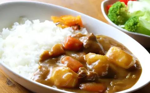 Pyszny ryż z curry, z kawałkami mięsa, ziemniaków i marchewki, podany z surówką.