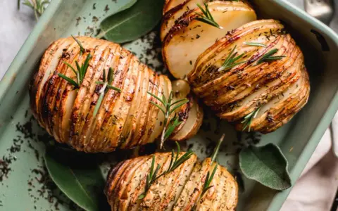 Pommes de terre Hasselback dorées et croustillantes, garnies de romarin frais. Une recette pomme de terre parfaite pour accompagner vos plats.