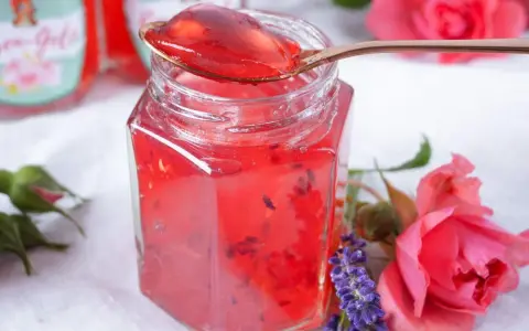 Ein Glas Sylter Rosenmarmelade, verziert mit Rosen und Lavendel. Ein köstliches Rezept für den Sommer.