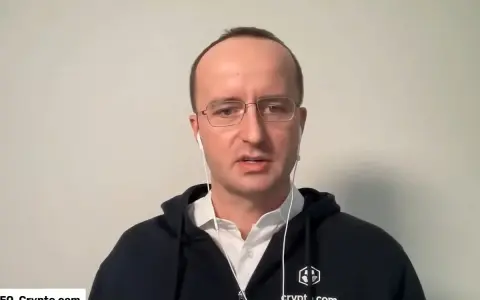 Kris Marszalek, CEO Crypto.com, w okularach i słuchawkach, w czarnej bluzie z logo.