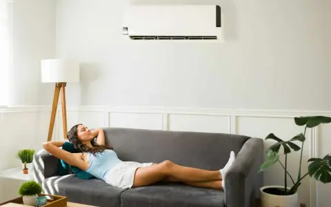 Une femme se détend sur un canapé sous un climatiseur, profitant de la puissance clim pour 40m2.