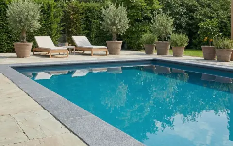Luxuriöser Pool mit Steinumrandung und mediterranen Pflanzen. Tolle pool verkleiden ideen für eine elegante Poollandschaft.