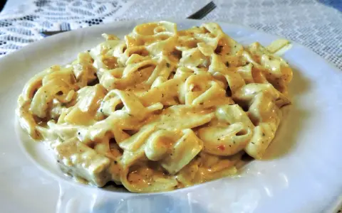 Pyszne tagliatelle z kurczakiem w kremowym sosie, podane na białym talerzu.