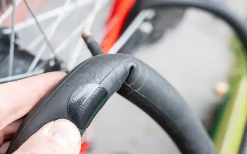 Dłoń trzyma załataną detkę rowerową, gotową do powrotu na swoje miejsce w oponie.