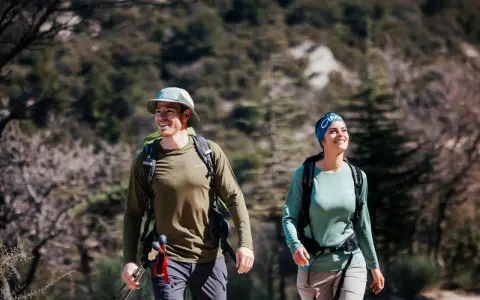 Randonneurs souriants malgré la chaleur, le mal de tête guette peut-être. Ils marchent sur un sentier rocailleux.