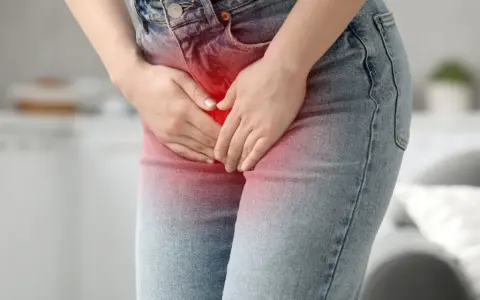 Kobieta trzyma się za podbrzusze, odczuwając ból brzucha przy zapaleniu pęcherza.