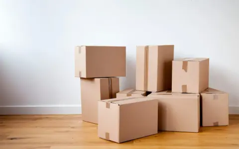 Stapel von braunen Kartons auf einem Holzboden, bereit für den Umzug oder zur Aufbewahrung.