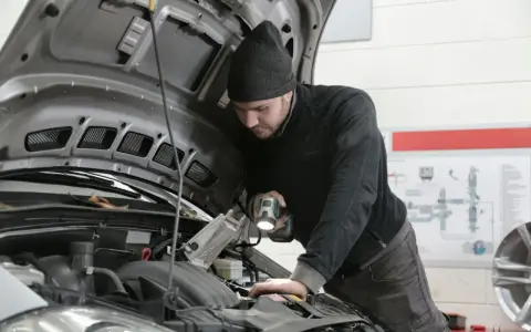 Mechanik z latarką bada silnik Forda, szukając przyczyny błędu DTC P0380.