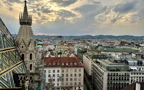 Blick über die Dächer Wiens bei Sonnenuntergang. Ein Turm des Stephansdoms ragt empor. Ein perfekter Moment, um Wien zu erleben.
