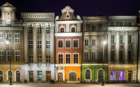 Nocny widok na kolorowe kamienice Starego Rynku w Poznaniu, przypominające urokliwe osiedle warszawskie.