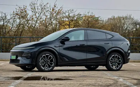 Elegancki, czarny Xpeng G6 stoi na parkingu, odbijając się w kałużach.