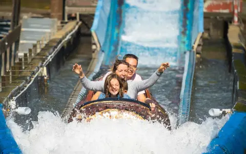 Familie hat Spaß auf einer spritzigen Wasserbahn im Freizeitpark.