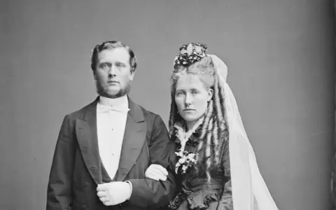 Brudpar i 1800-talets kläder, en viktig del av giftermål historia. Mannen bär frack, kvinnan slöja och blommor.
