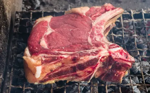 Bistecca alla fiorentina cruda su griglia, pronta per la cottura. Il tempo cottura fiorentina è fondamentale per una perfetta riuscita.