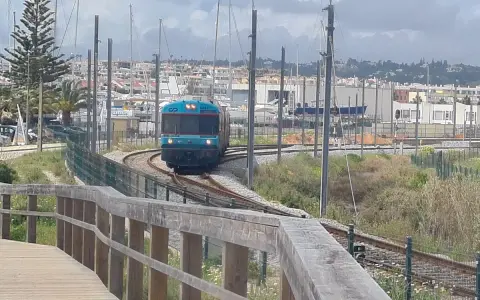 Ein Zug fährt auf den Gleisen in Richtung einer Marina mit vielen Segelbooten. Die Fahrt von Lissabon in die Algarve ist ein Erlebnis.