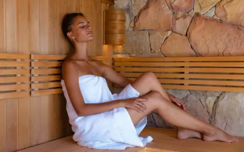 Kobieta w saunie, relaksująca się w ciszy. Zastanawiasz się, ile kcal spala sauna? To świetny sposób na odprężenie i wsparcie metabolizmu.