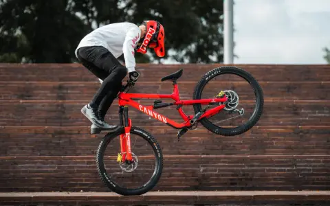 Gabriel Wibmer balanciert auf seinem roten Canyon Bike auf einer Treppe.