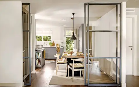 Separación pared cristal cocina salón. Una puerta corredera de cristal divide la cocina del salón, creando un espacio abierto y luminoso.