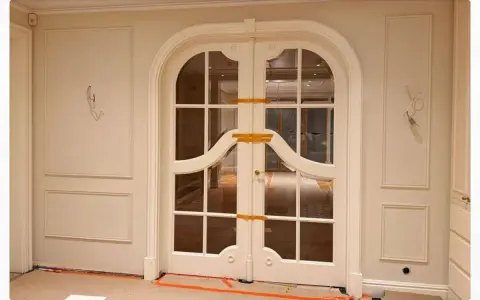 Eleganckie drzwi dwuskrzydłowe z łukiem i ozdobną sztukaterią. Planowanie sztukaterii wokół drzwi podkreśla ich styl.