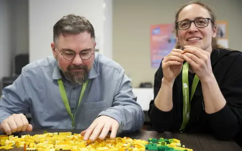 Zwei Personen bauen mit bunten Legosteinen, während sie an einem software architecture summit teilnehmen.