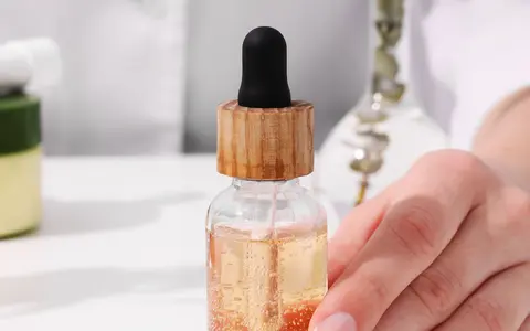Dłoń trzymająca serum z pipetką. Składniki takie jak EDTA w kosmetykach pomagają stabilizować formuły.