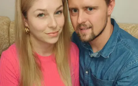 Zbliżenie na twarze pary siedzącej obok siebie na kanapie.