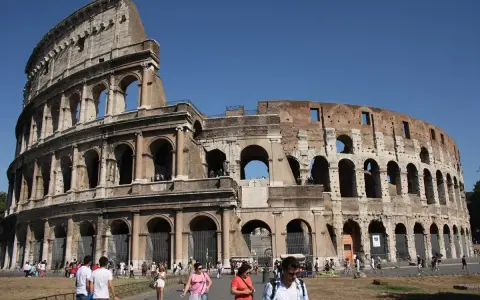 Le Colisée de Rome avant sa restauration complète, avec des touristes admirant son architecture antique sous un ciel bleu.