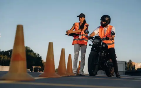 Instruktorka motocyklowa obserwuje kursanta podczas ćwiczeń na placu. Zastanawiasz się, ile godzin jazdy na kat. A potrzeba, by zdać egzamin?