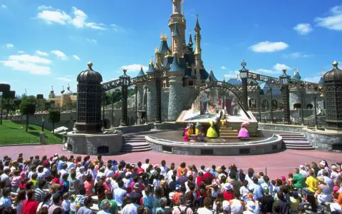 Disneyland Paris con niños: un espectáculo de princesas frente al castillo, con una multitud emocionada disfrutando del día.