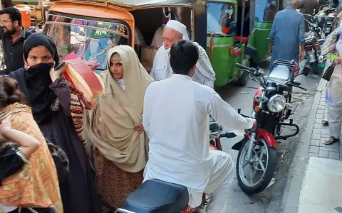 Ludzie na ulicy w Pakistanie, wśród nich kobiety w hidżabach i dzieci. Czy pakistan jest bezpieczny? Tłum na targu, ruchliwa ulica.