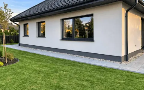 Nowy dom z zadbanym ogrodem i ścieżką wokół. To najtańsza opaska wokół domu, która dodaje uroku.